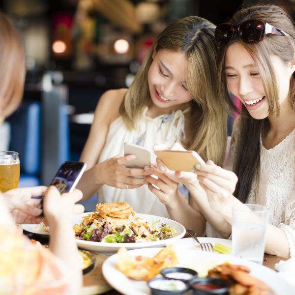 happy friends with smart phones taking picture of food at restaurant